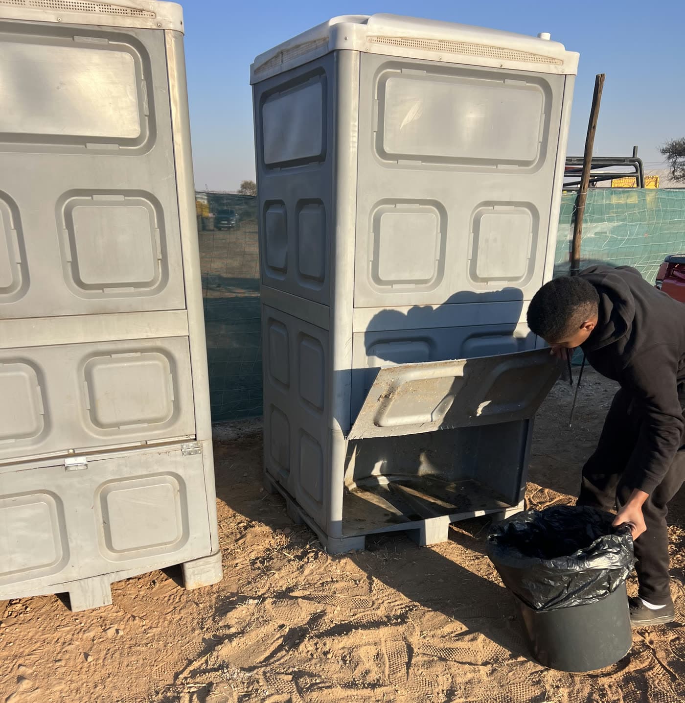 Mahapa Event Hire staff member removing the sealed waste container from a chemical toilet during a service on a construction site